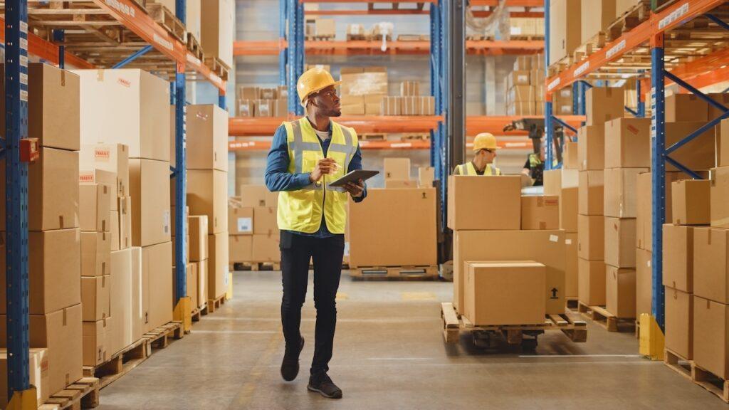 Ein Logistikmitarbeiter nutzt mobile Datenerfassung per Tablet, um Bestände und Wareneingänge zu verwalten.