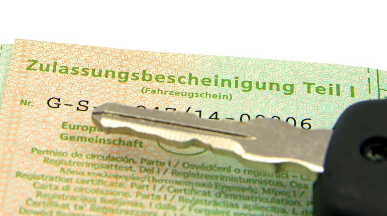 Zulassungsbescheinigung Teil 1 mit Autoschlüssel in Nahaufnahme – Dokumente zum Auto abmelden bereitgelegt